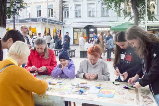Две женщины на мастер-классе очень старательно складывали цветки, а потом даже подсказывали порядок сложения лепестков только что подошедшим детям