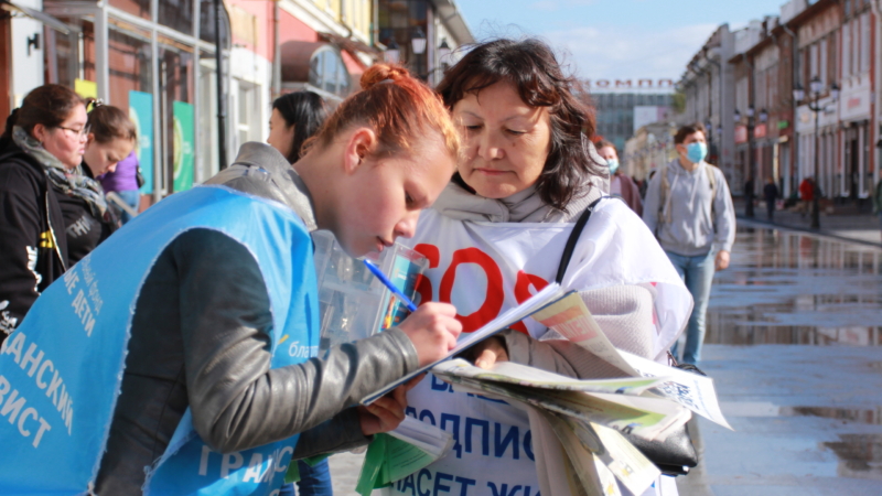 Прохожие подписывают Петицию против насильственного извлечения органов у практикующих Фалунь Дафа