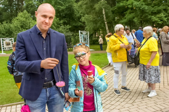 Гости праздника День города с удовольствием фотографировались, держа в руках цветки лотоса. Ленинградская обл., г. Зеленогорск, 30.07.2022 г.