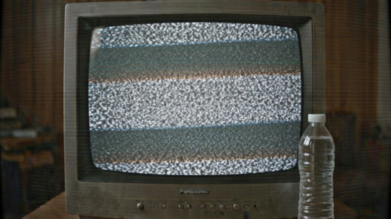 Старый телевизор Panasonic с помехами на экране и бутылка воды